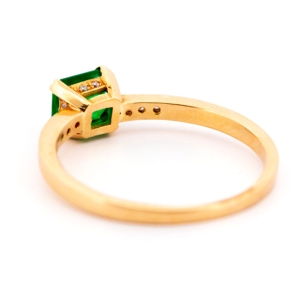 A step cut emerald ring with diamond shoulders, in yellow gold