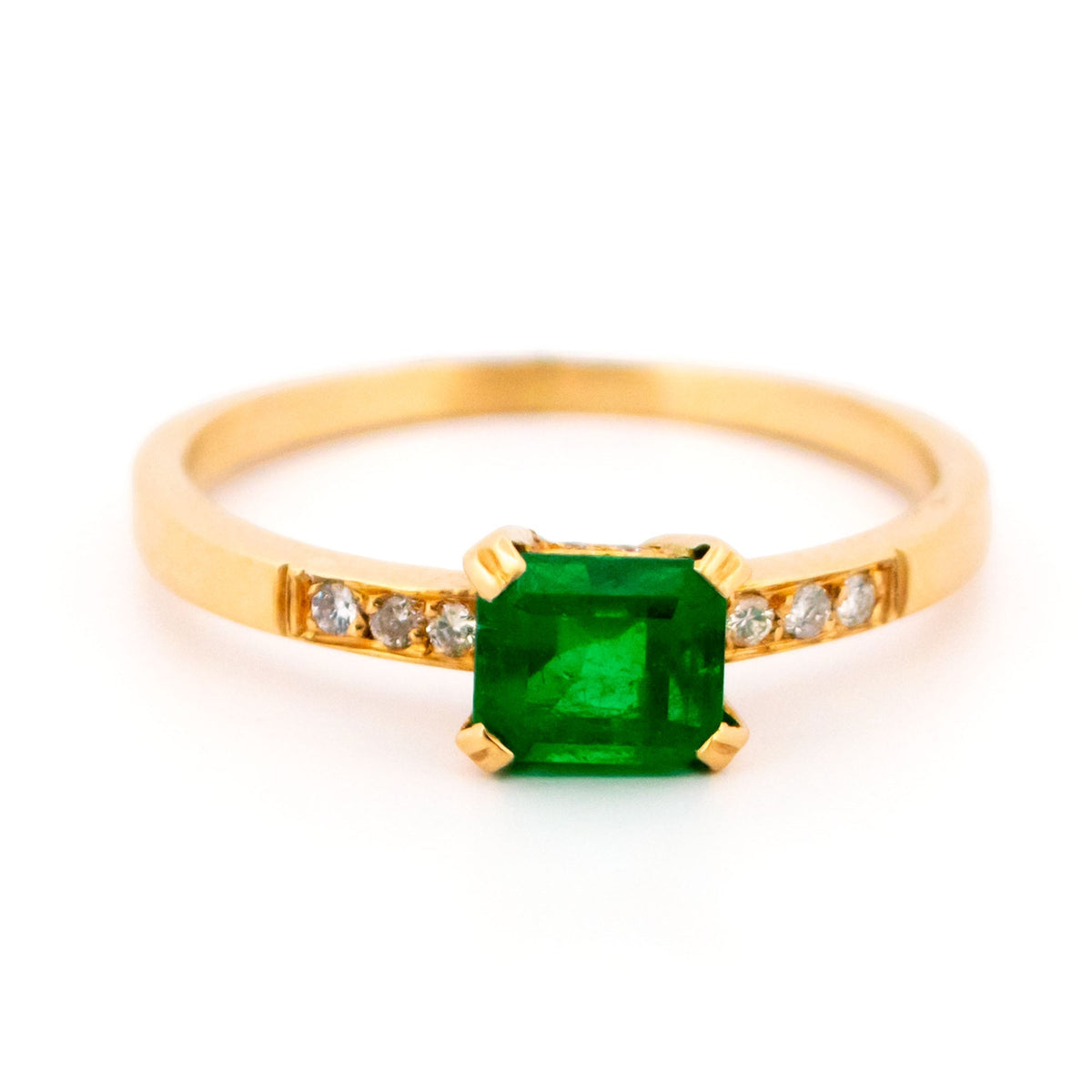 A step cut emerald ring with diamond shoulders, in yellow gold