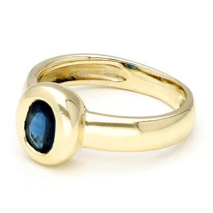 Yellow gold ring with a solitaire oval sapphire, against a white background