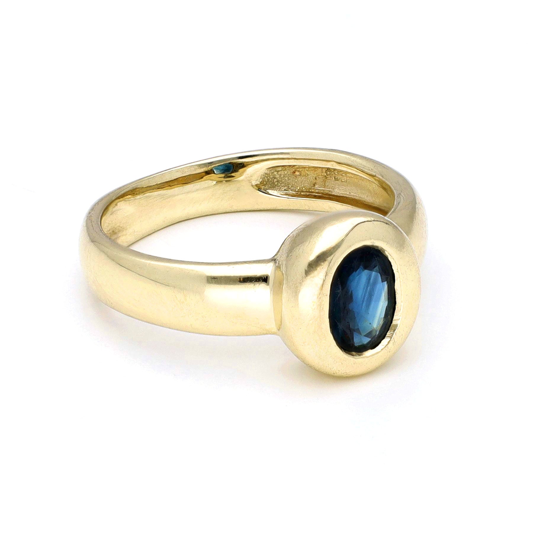 Yellow gold ring with a solitaire oval sapphire, against a white background