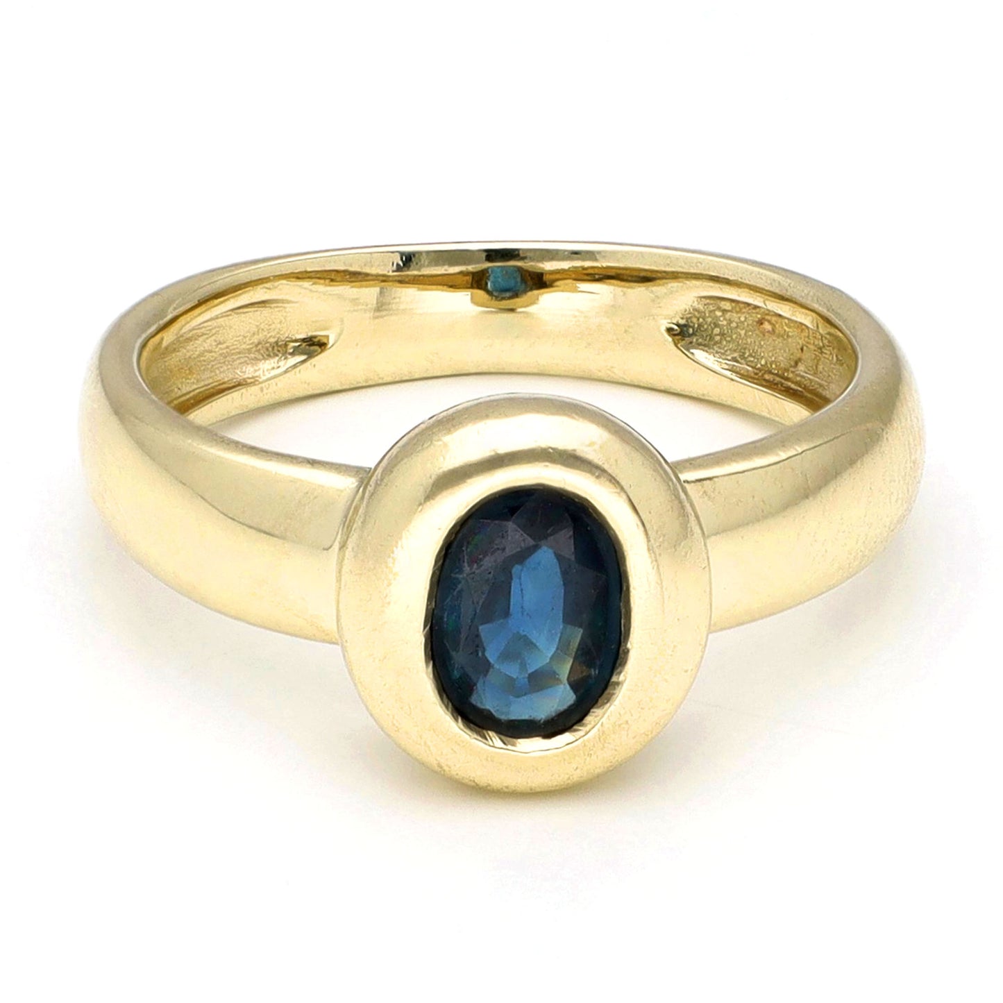 Yellow gold ring with a solitaire oval sapphire, against a white background