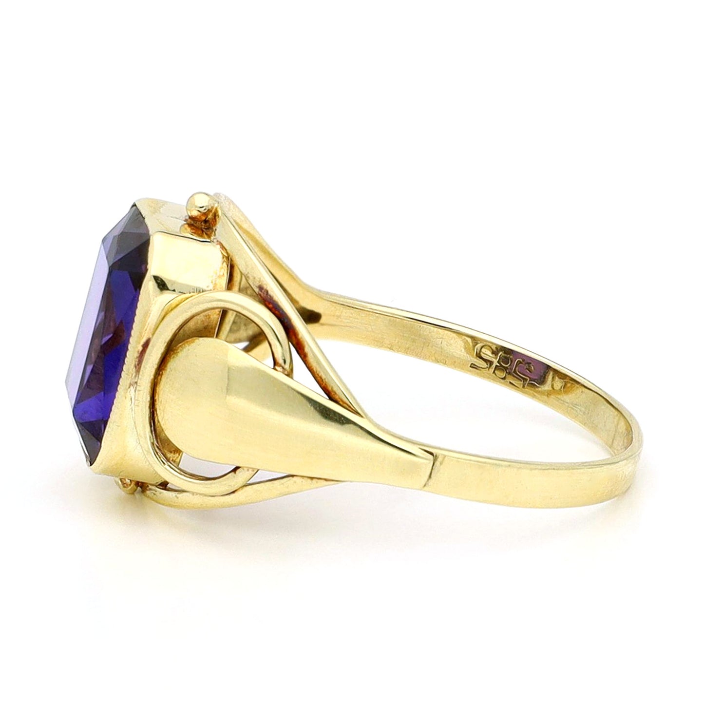 A yellow gold emerald cut amethyst ring, against a white background
