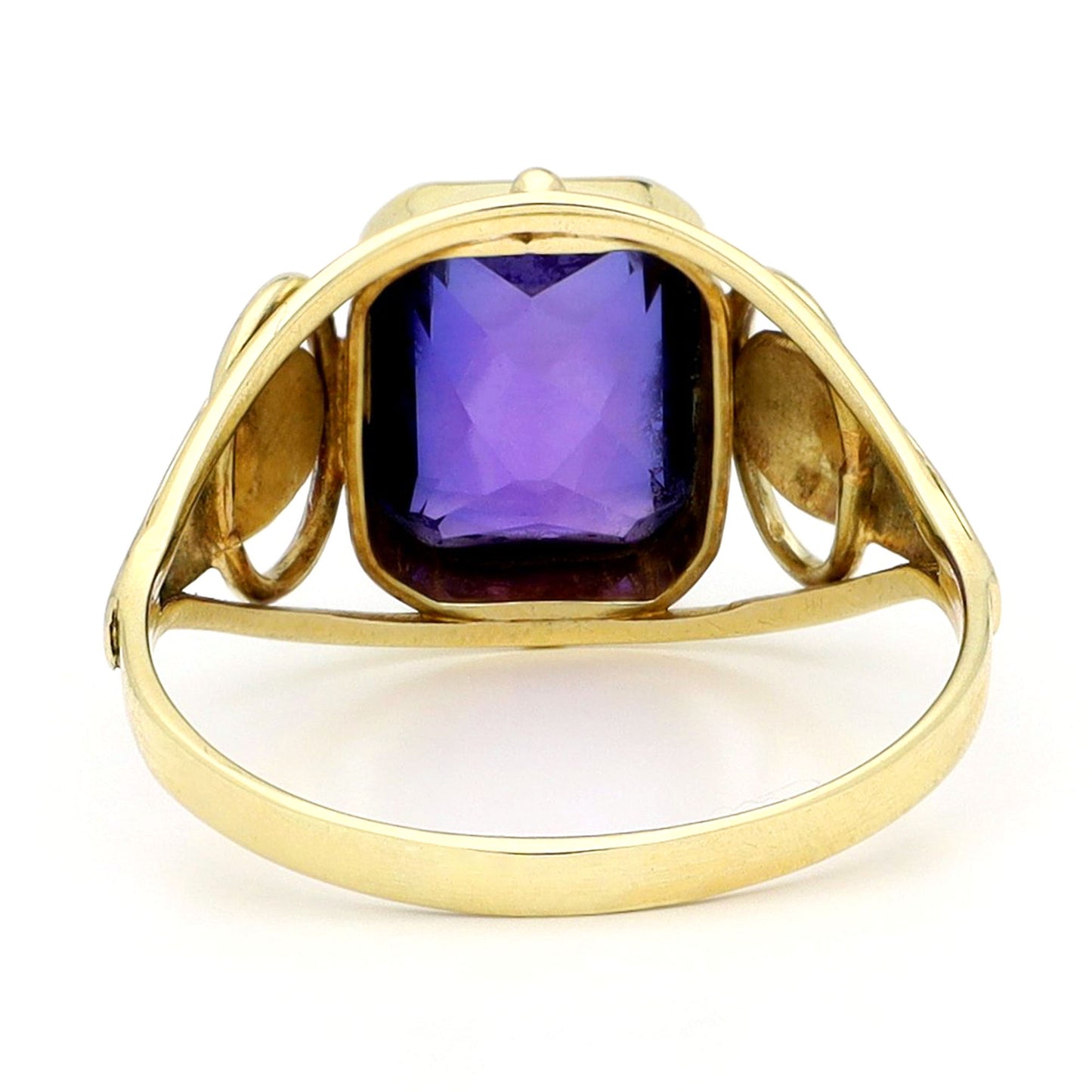 A yellow gold emerald cut amethyst ring, against a white background