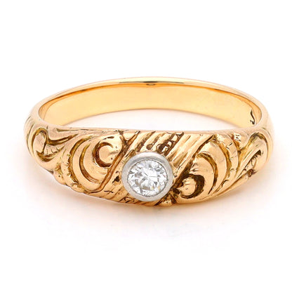 A yellow gold ring with a single old cut diamond bezel set in white gold, with scroll engraving, against a white background