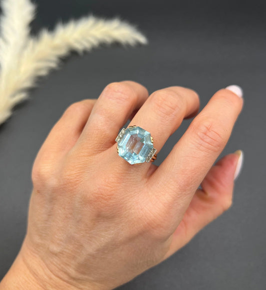 An octagonal cut aquamarine and diamond cocktail ring in yellow gold, modelled on a hand