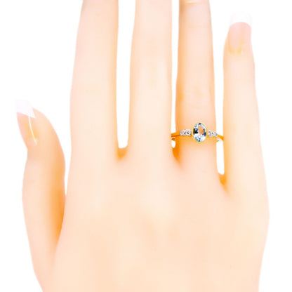 An oval aquamarine and round diamond ring in yellow and white gold, modelled on a hand
