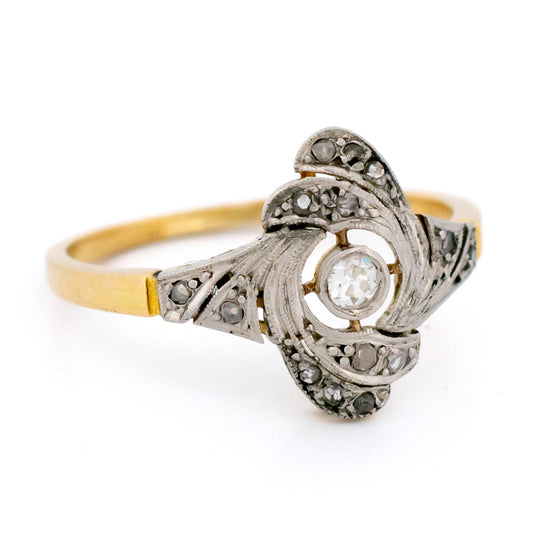 A yellow gold and platinum swirl design ring with diamonds