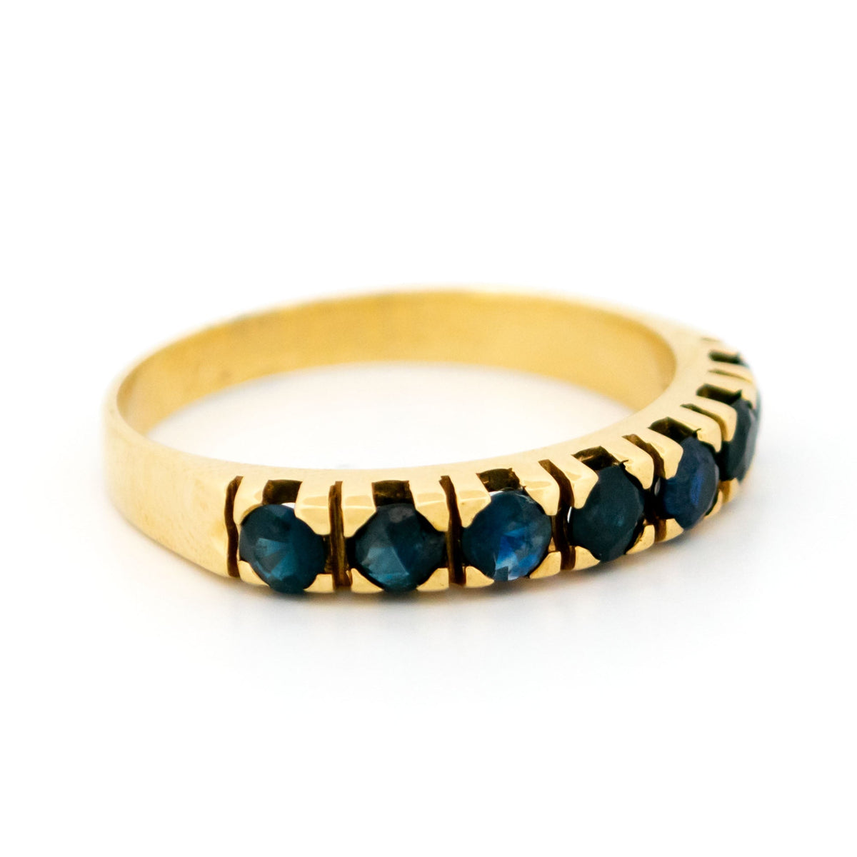 A seven stone round sapphire band ring in yellow gold
