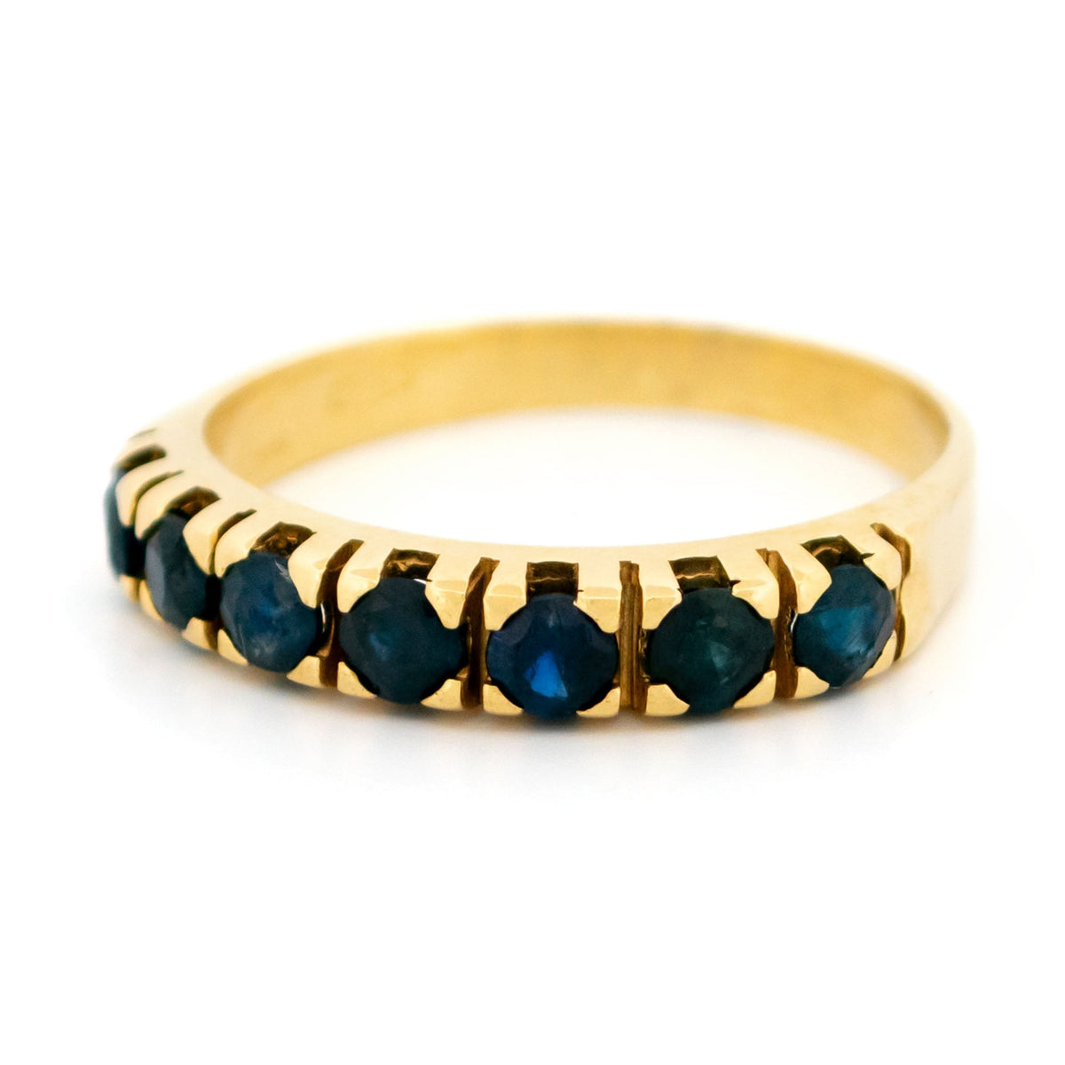 A seven stone round sapphire band ring in yellow gold