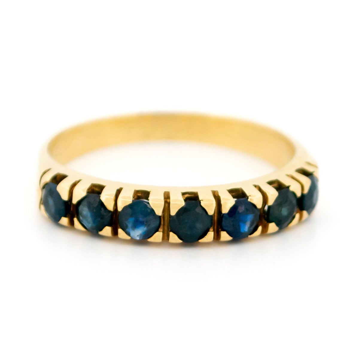 A seven stone round sapphire band ring in yellow gold