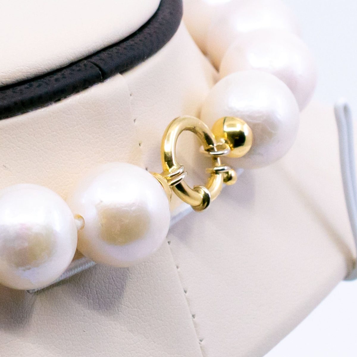A white cultured pearl necklace, with a yellow gold clasp