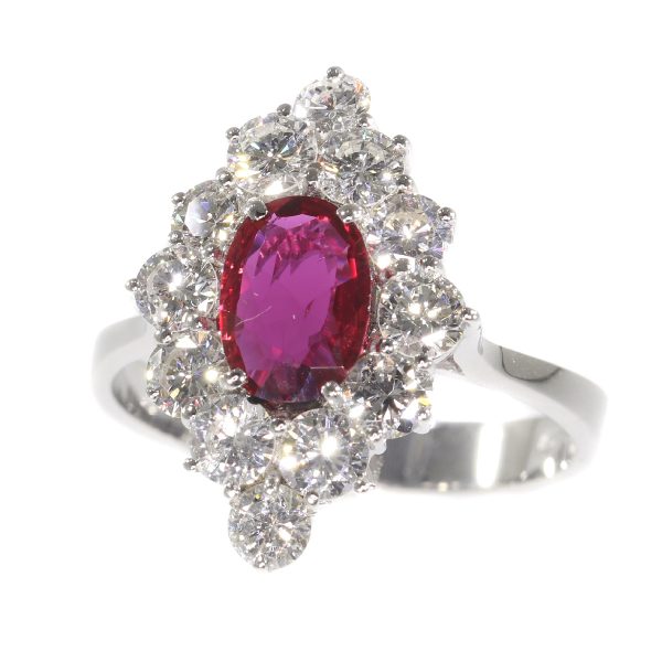 Vintage Ruby and Diamond Cluster Ring; featuring an 0.80ct oval faceted ruby surrounded by 1.80cts round brilliant-cut diamonds, in 18ct white gold. Circa 1970s