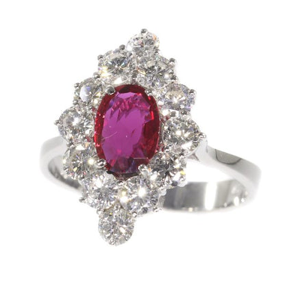 Vintage Ruby and Diamond Cluster Ring; featuring an 0.80ct oval faceted ruby surrounded by 1.80cts round brilliant-cut diamonds, in 18ct white gold. Circa 1970s