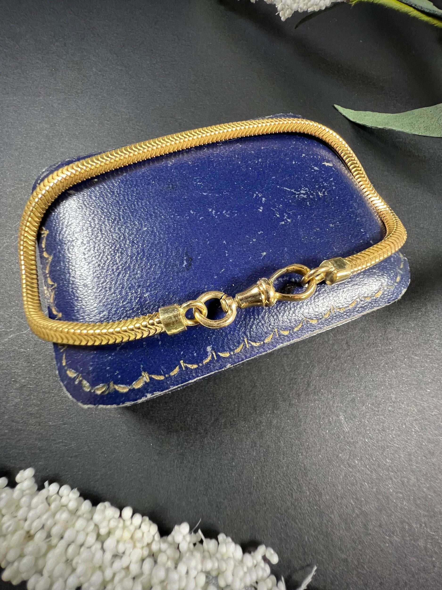 A yellow gold snake link bracelet, laid on a blue antique box