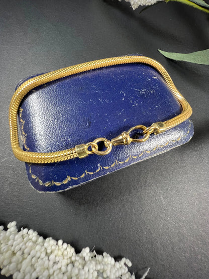 A yellow gold snake link bracelet, laid on a blue antique box