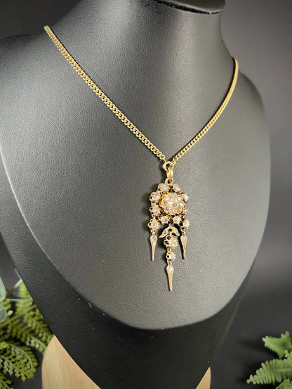A yellow gold pendant with old cut diamonds, with a gold chain, modelled on a black jewellery bust