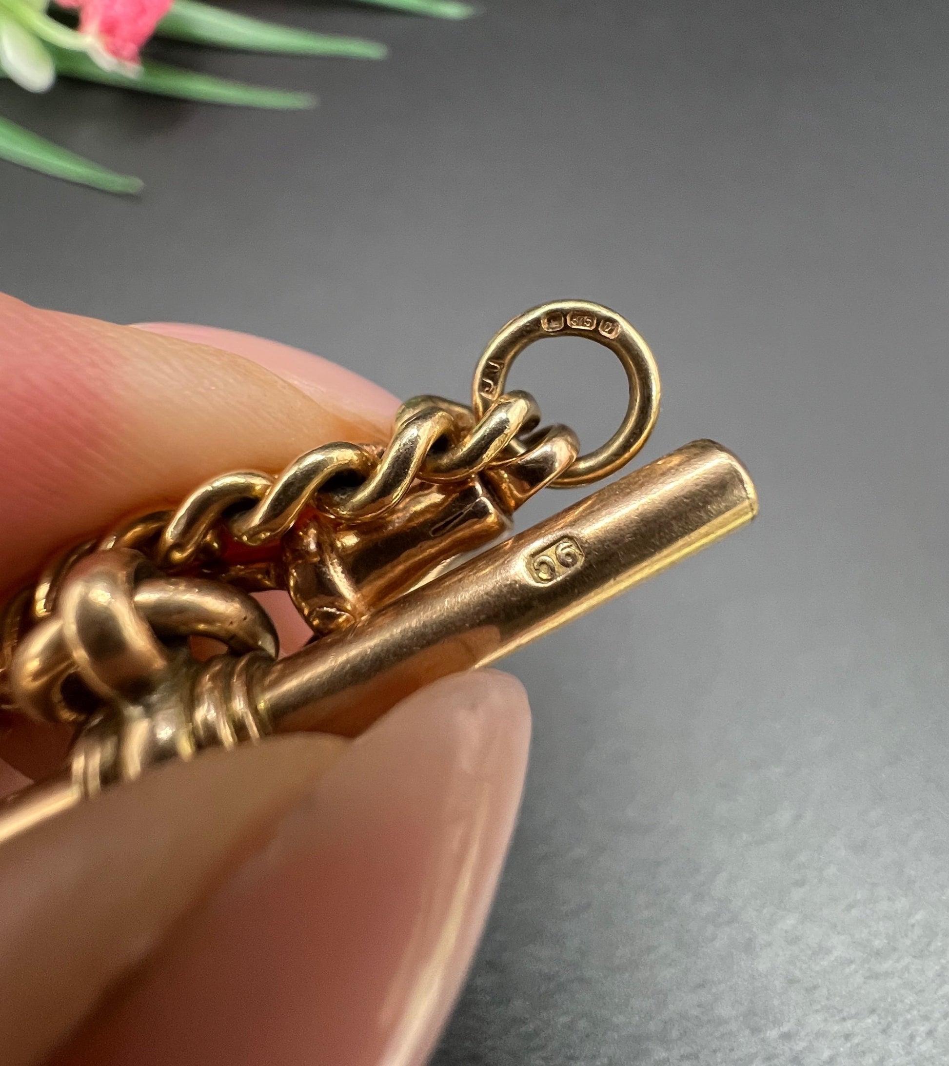 Close-up of a gold t-bar stamped 9C, held by a hand