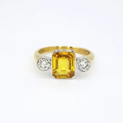 2.25ct Emerald Cut Yellow Sapphire and Diamond Three Stone Ring; central 2.25ct emerald-cut yellow sapphire flanked by 0.50cts brilliant-cut diamonds, 18ct yellow gold shank