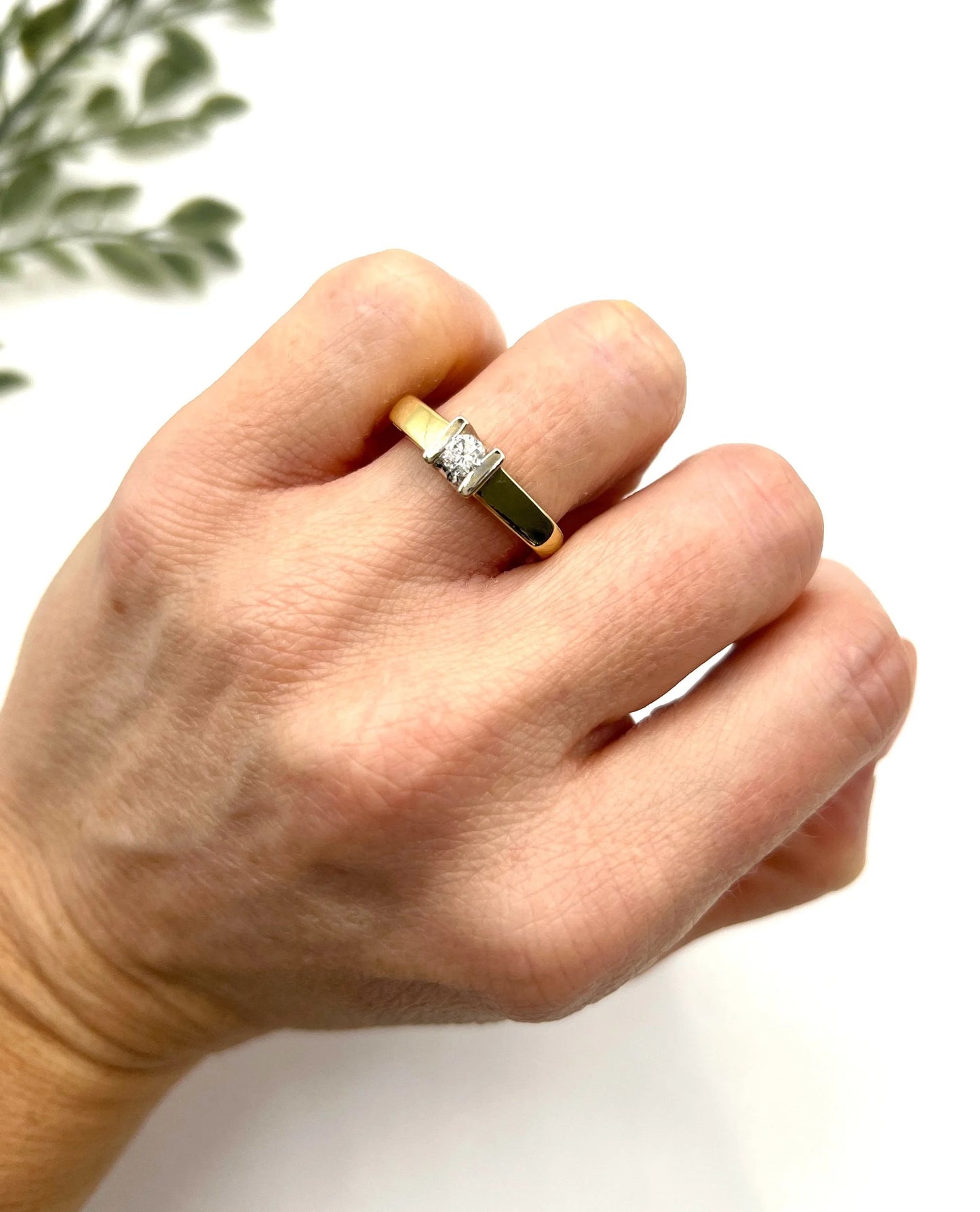 A brilliant cut diamond solitaire ring in yellow gold, modelled on a hand