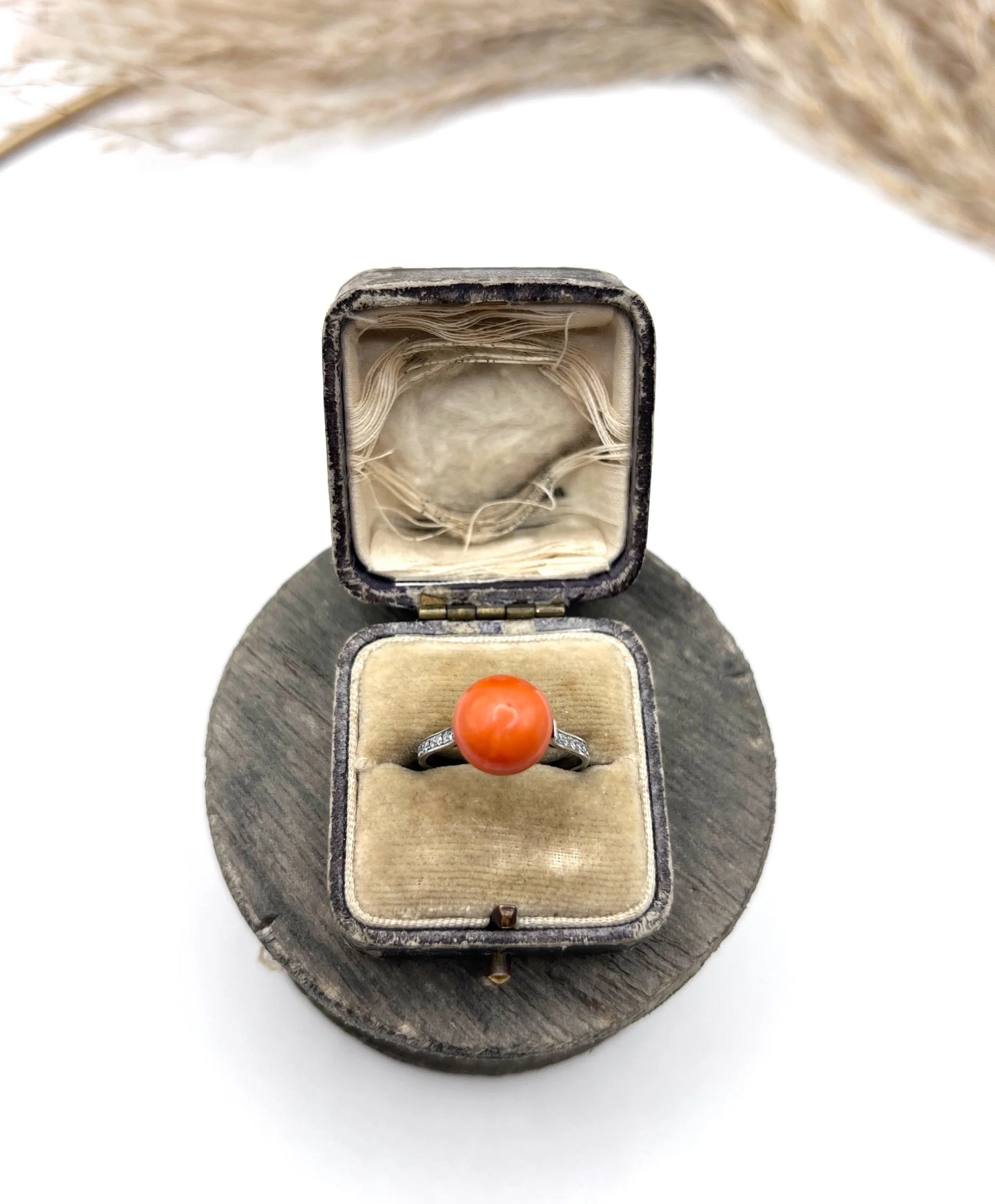 A round orange coral and diamond dress ring in platinum, in an antique ring box