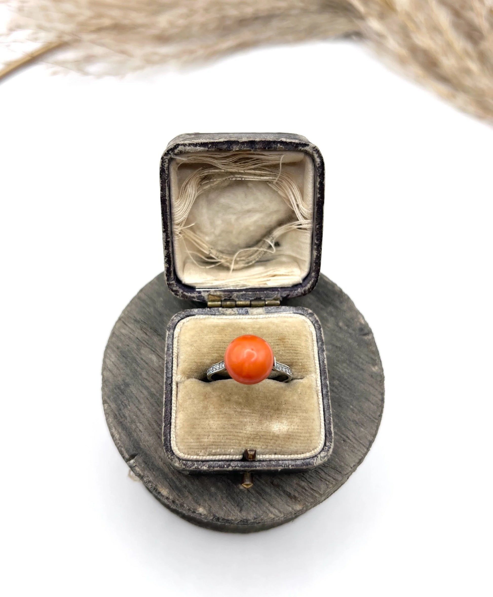 A round orange coral and diamond dress ring in platinum, in an antique ring box