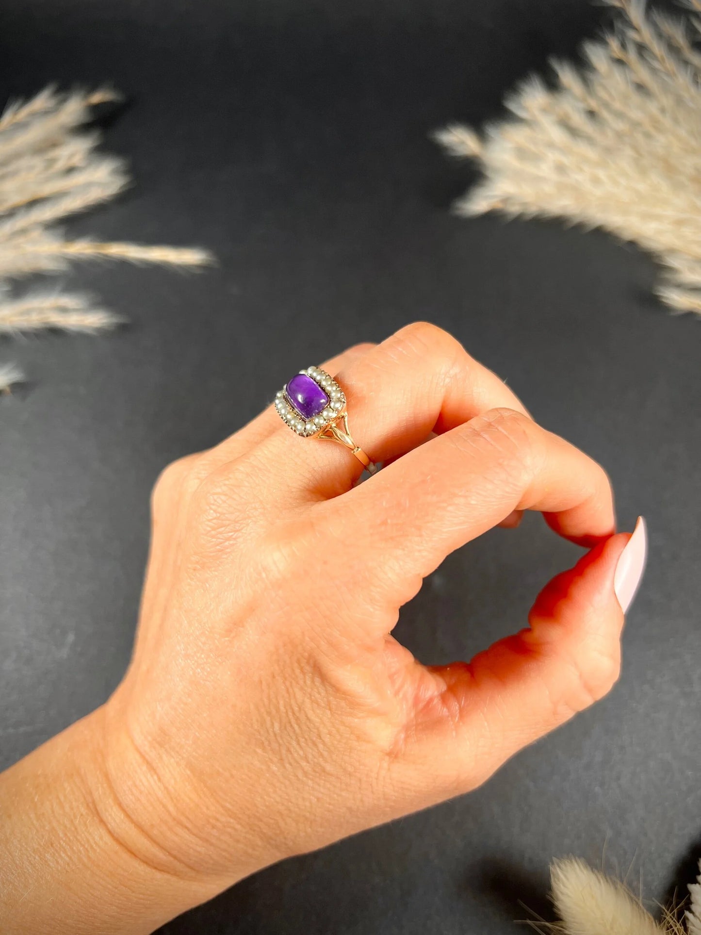 A cabochon amethyst and pearl halo cluster ring in gold, modelled on a hand
