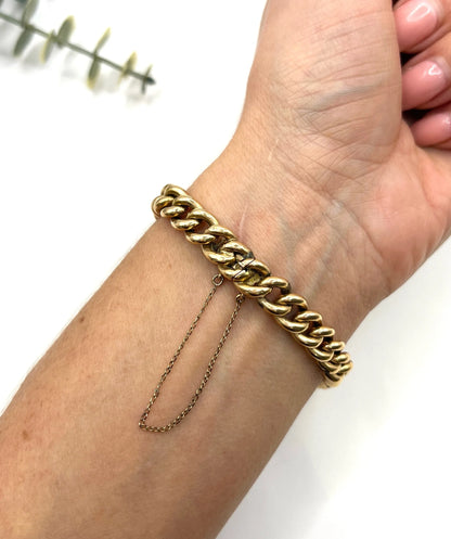 A curb link bracelet with a safety chain in yellow gold, modelled on a wrist