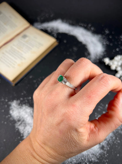 A three stone emerald and diamond ring in platinum, modelled on a hand