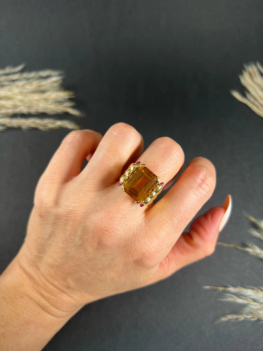 An emerald cut citrine and cabochon ruby yellow gold cocktail ring, modelled on a hand
