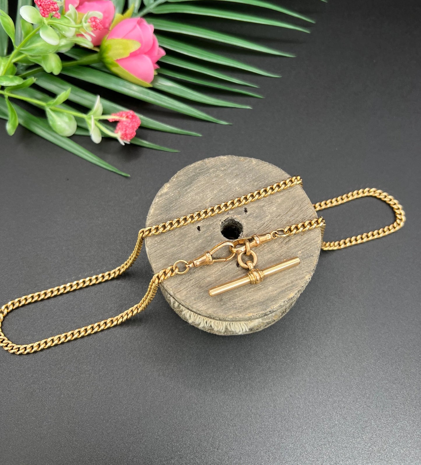 A gold curb link Albert chain, on a wooden spool