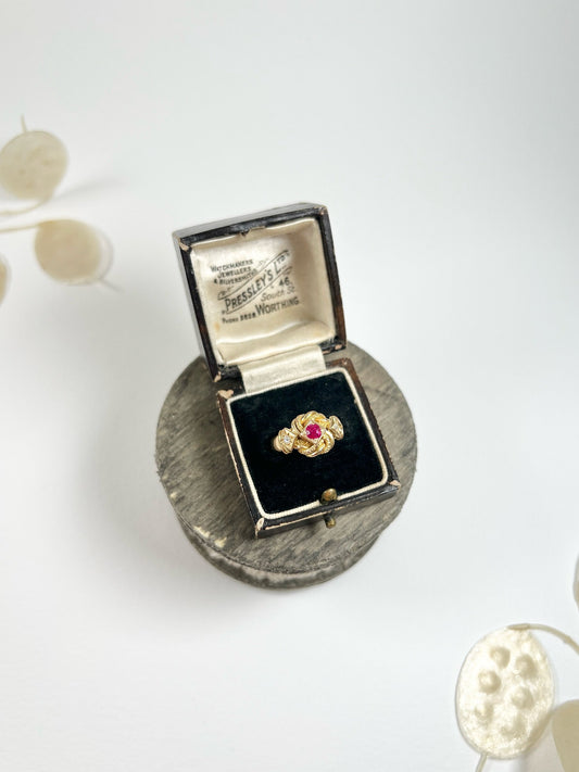 A yellow gold ruby and diamond three stone knot ring, in a ring box
