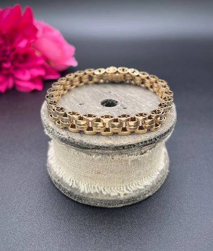 A yellow gold link bracelet, on a wooden spool