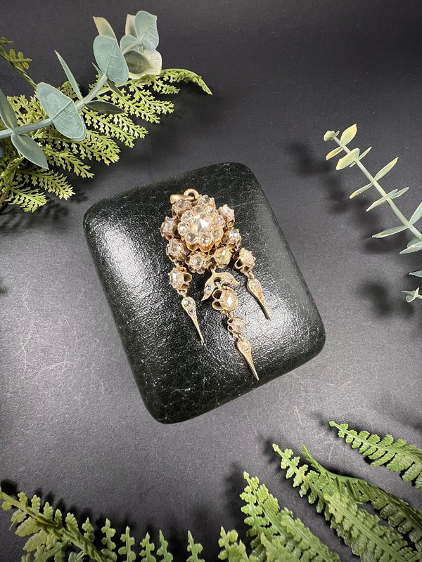 A yellow gold pendant with old cut diamonds, on a black antique box