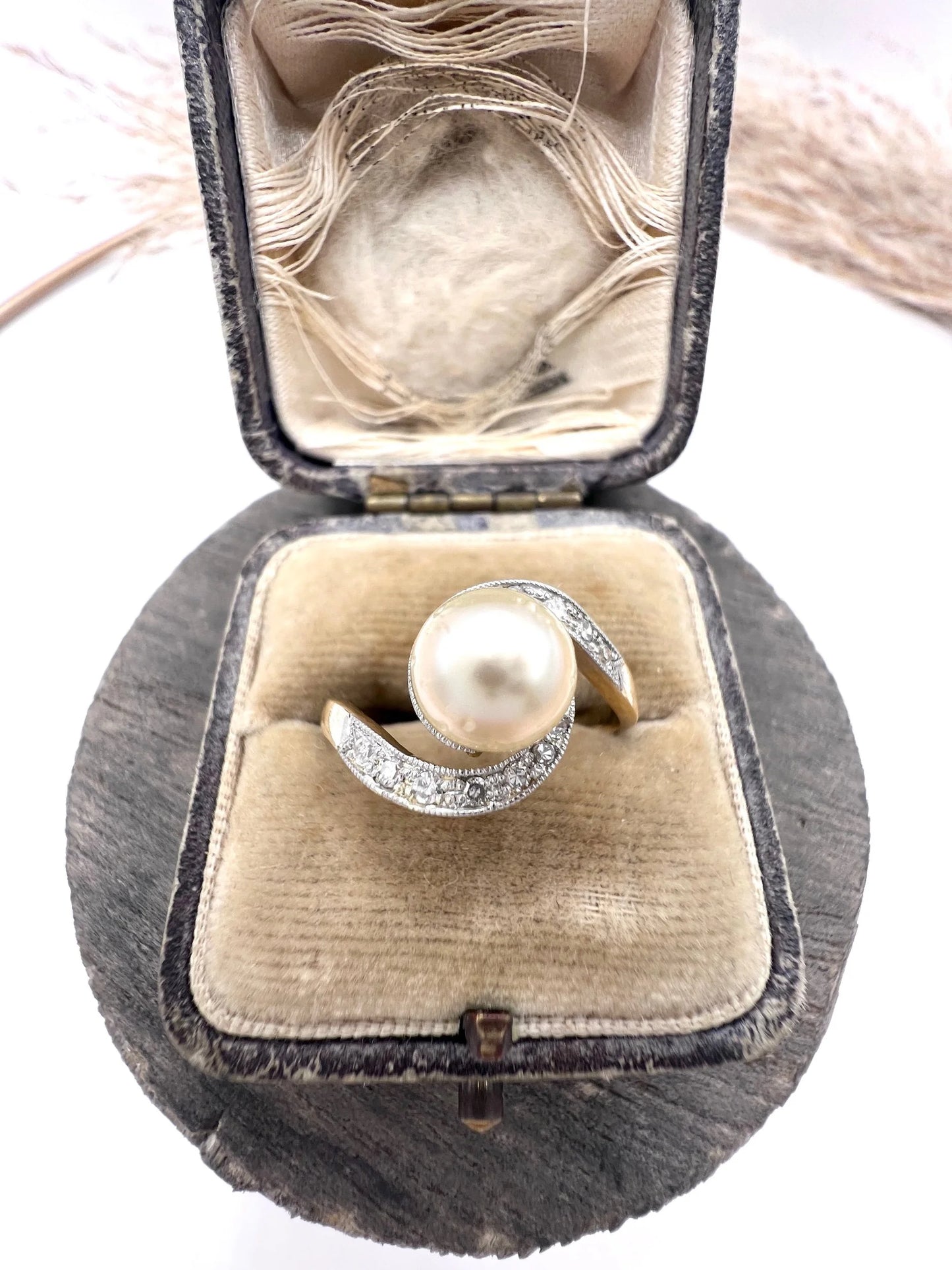 A pearl and diamond crossover swirl ring in yellow and white gold, in an antique ring box