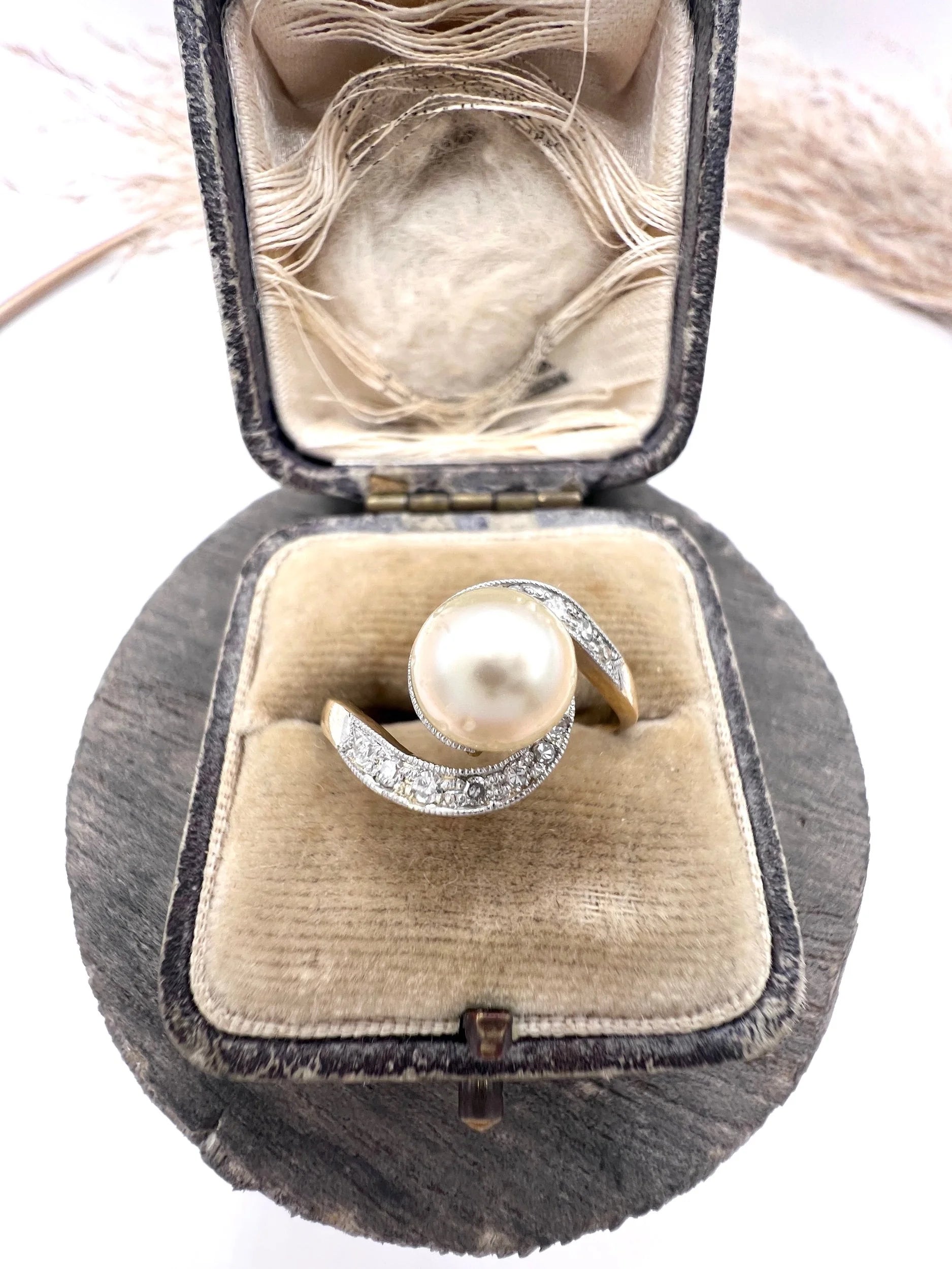 A pearl and diamond crossover swirl ring in yellow and white gold, in an antique ring box