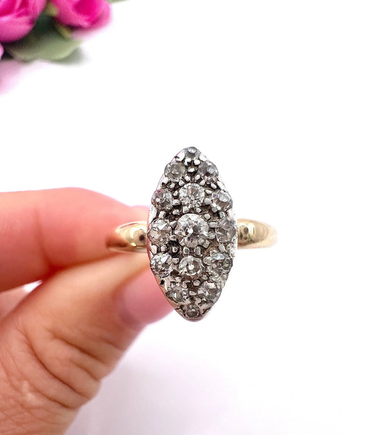 A navette cluster ring set with old cut diamonds in yellow gold, held in a hand