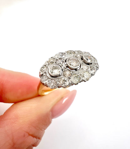 A diamond triple cluster ring in yellow and white gold, held in a hand