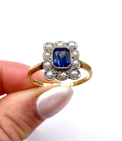 A sapphire and pearl cluster ring in yellow gold and platinum, held in a hand