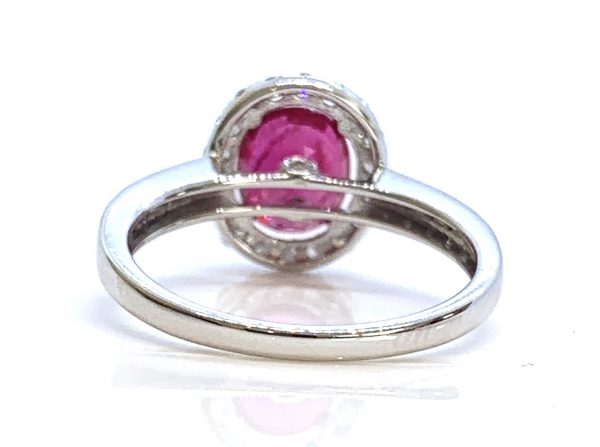 Ruby and Diamond Halo Cluster Engagement Ring; 1.71ct oval ruby with no indication of heat treatment with diamond halo and diamond shoulders, 18ct white gold