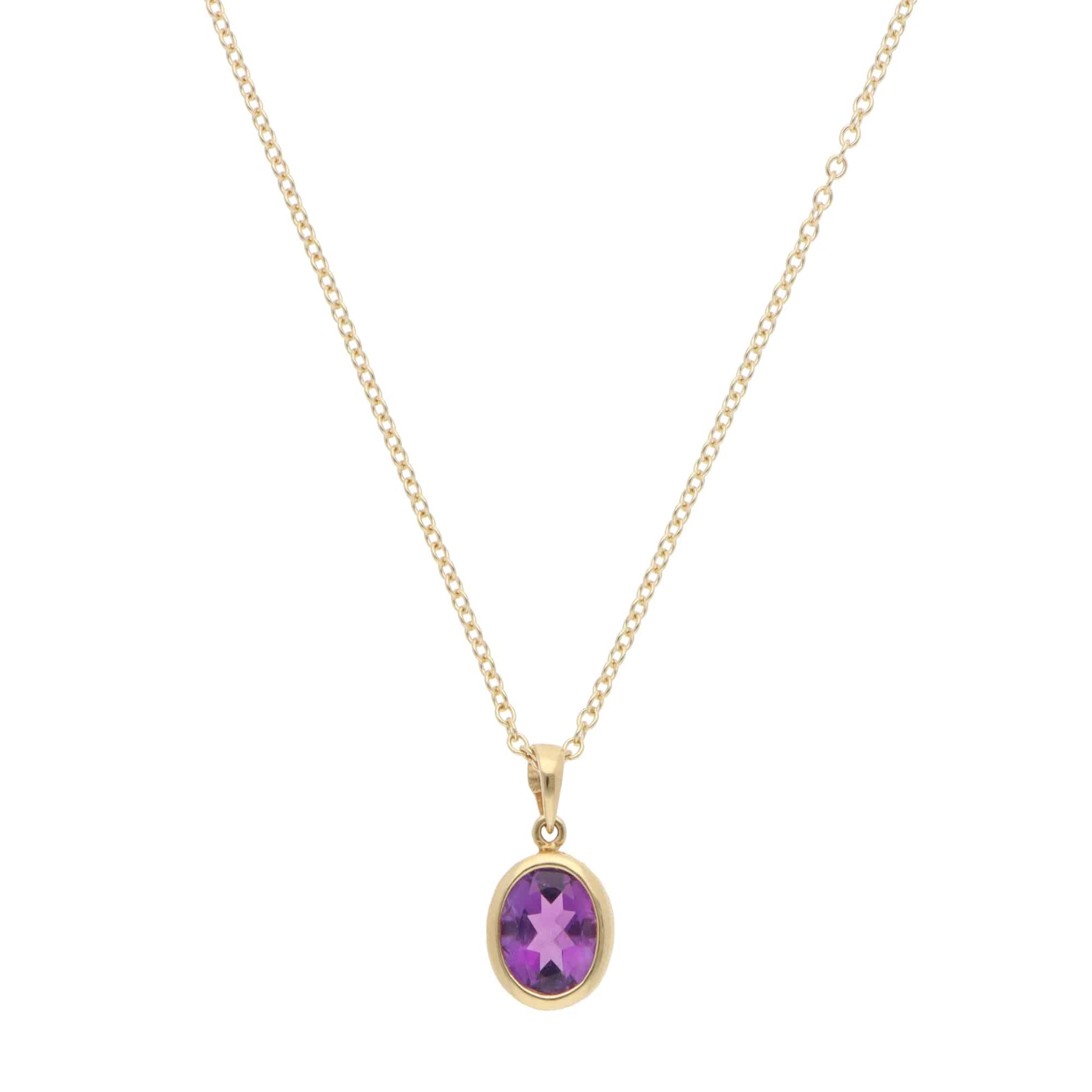 A yellow gold amethyst pendant on a gold chain, on a white background
