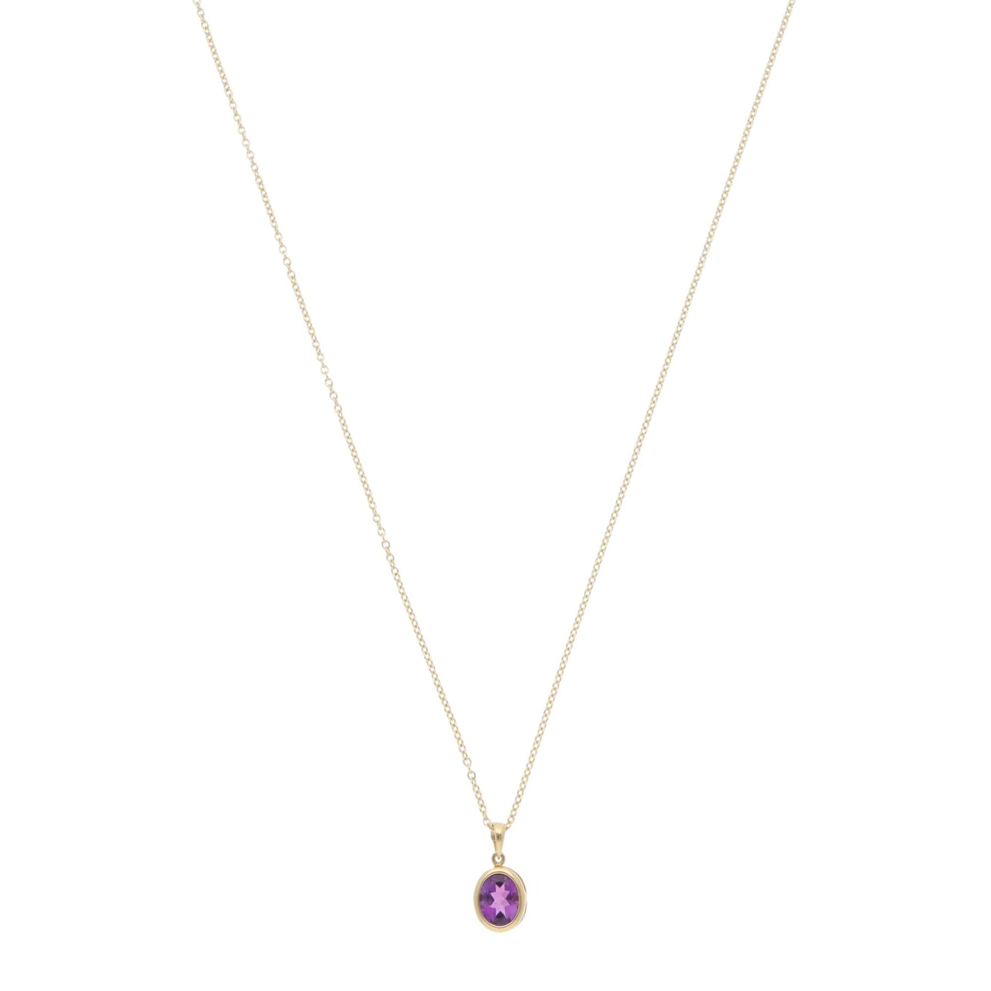 A yellow gold amethyst pendant on a gold chain, on a white background