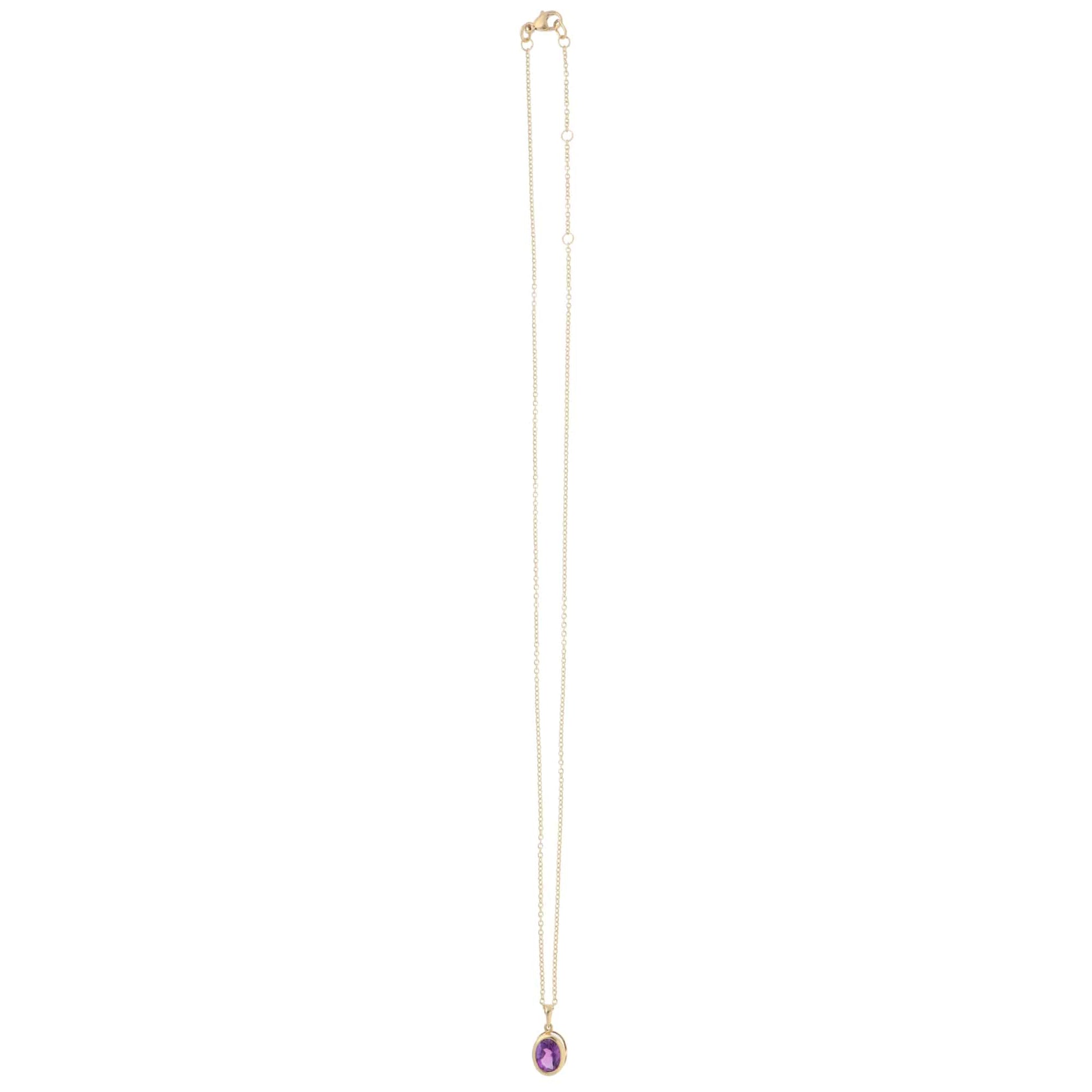 A yellow gold amethyst pendant on a gold chain, on a white background