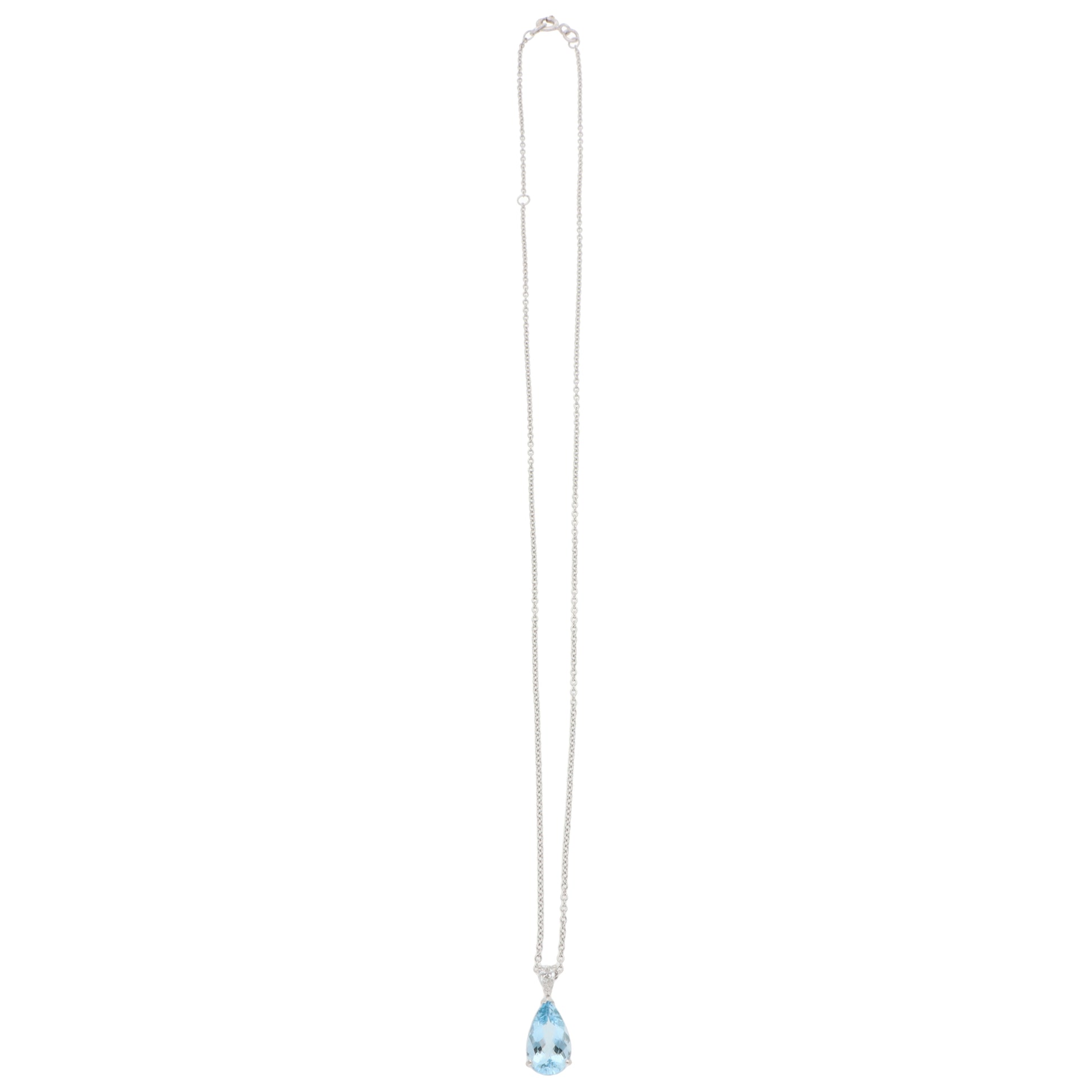 A pear shaped aquamarine and diamond pendant on a white gold chain, on a white background
