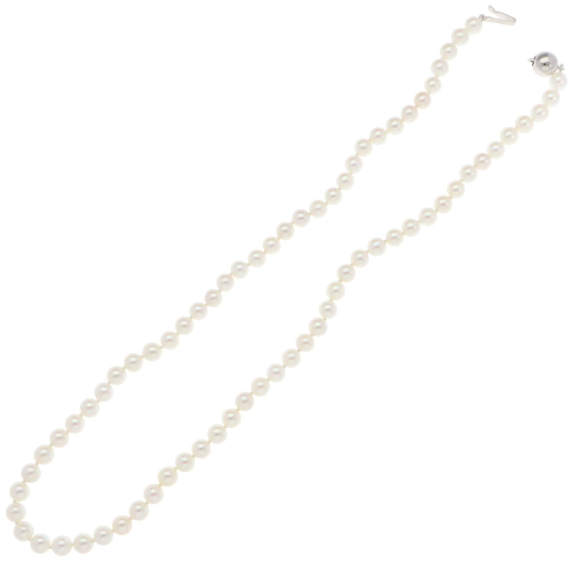 A white pearl single row necklace with a white gold clasp, on a white background