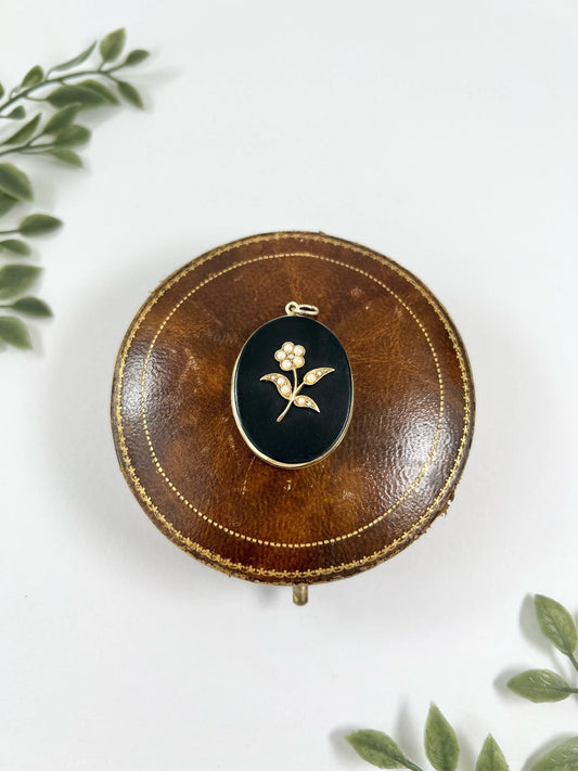 An oval onyx, pearl and yellow gold locket