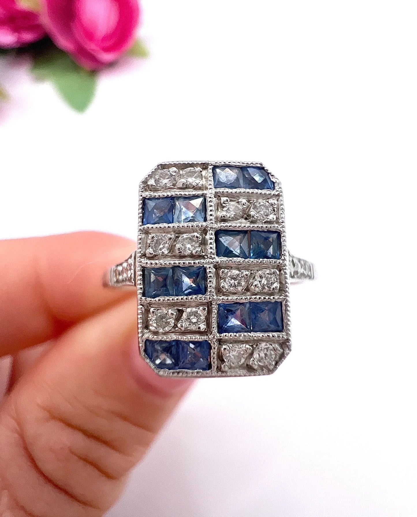 A sapphire and diamond tablet style ring in platinum, held in a hand