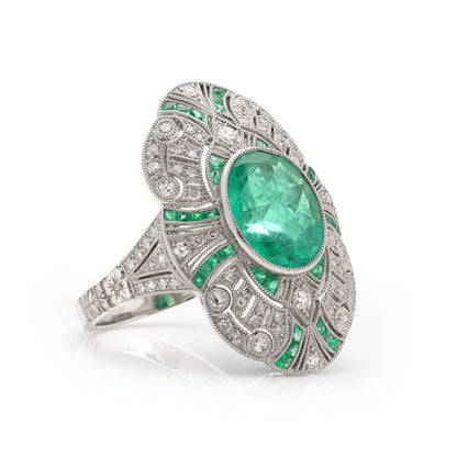 Oval cut emerald ring surround by emeralds and diamonds set in platinum.