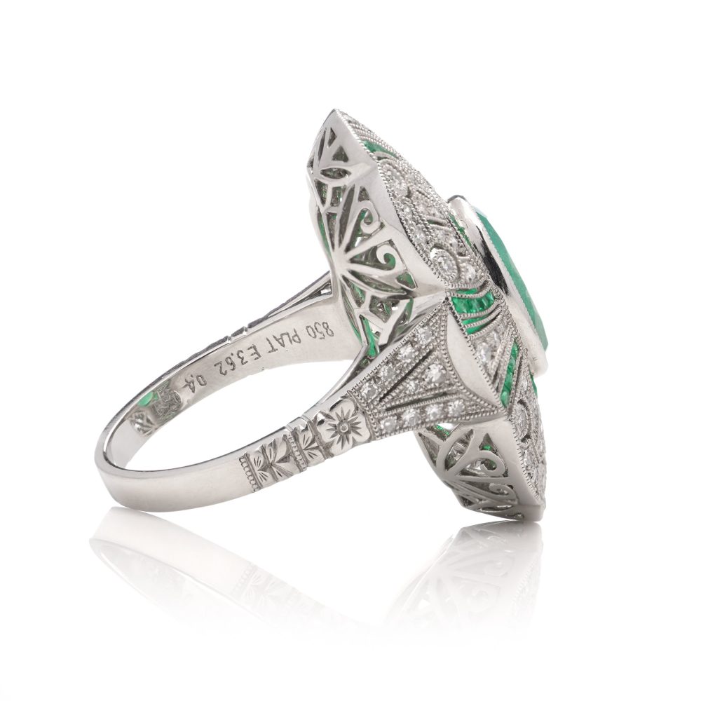Oval cut emerald ring surround by emeralds and diamonds set in platinum.