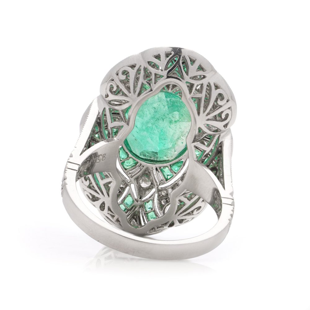 Oval cut emerald ring surround by emeralds and diamonds set in platinum.