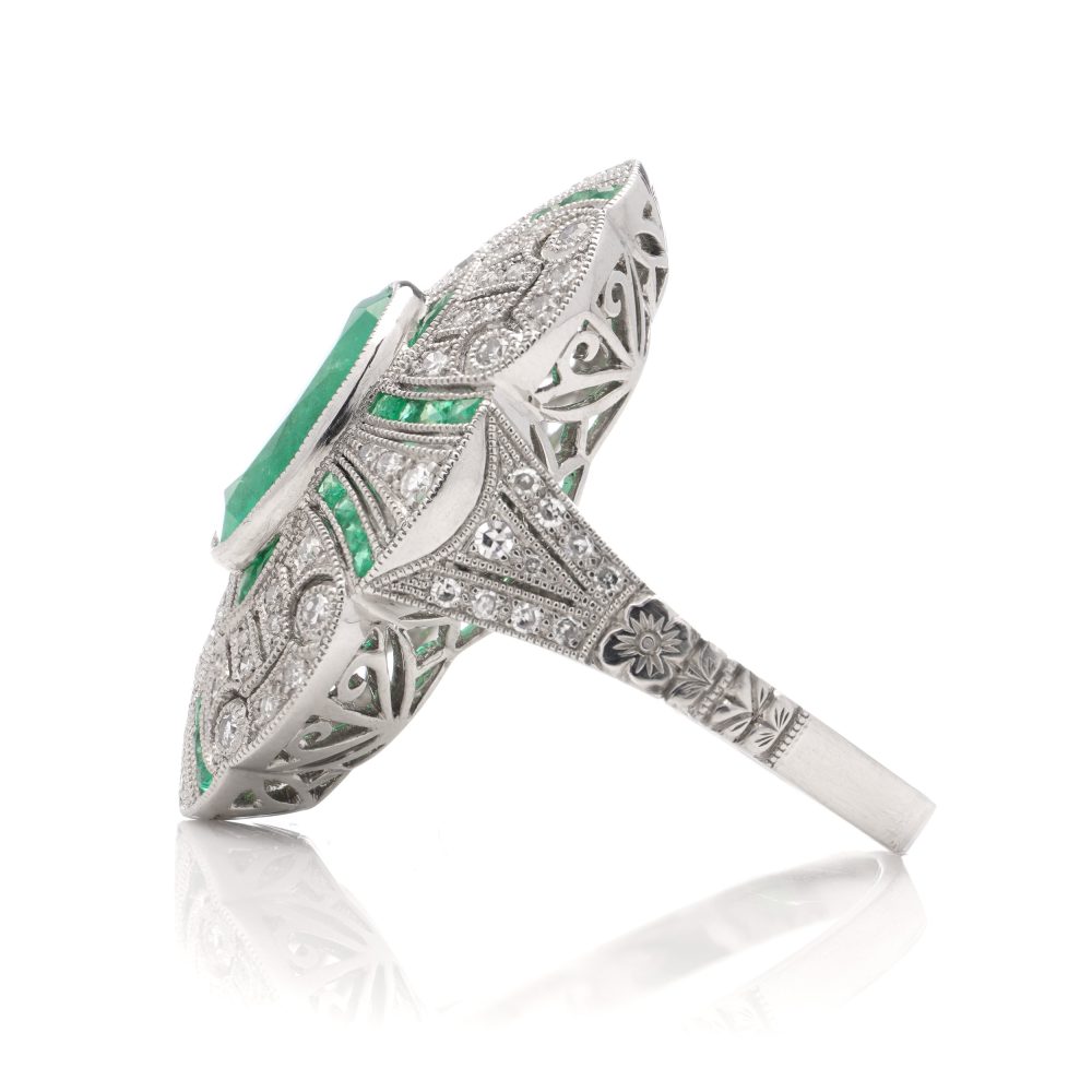 Oval cut emerald ring surround by emeralds and diamonds set in platinum.